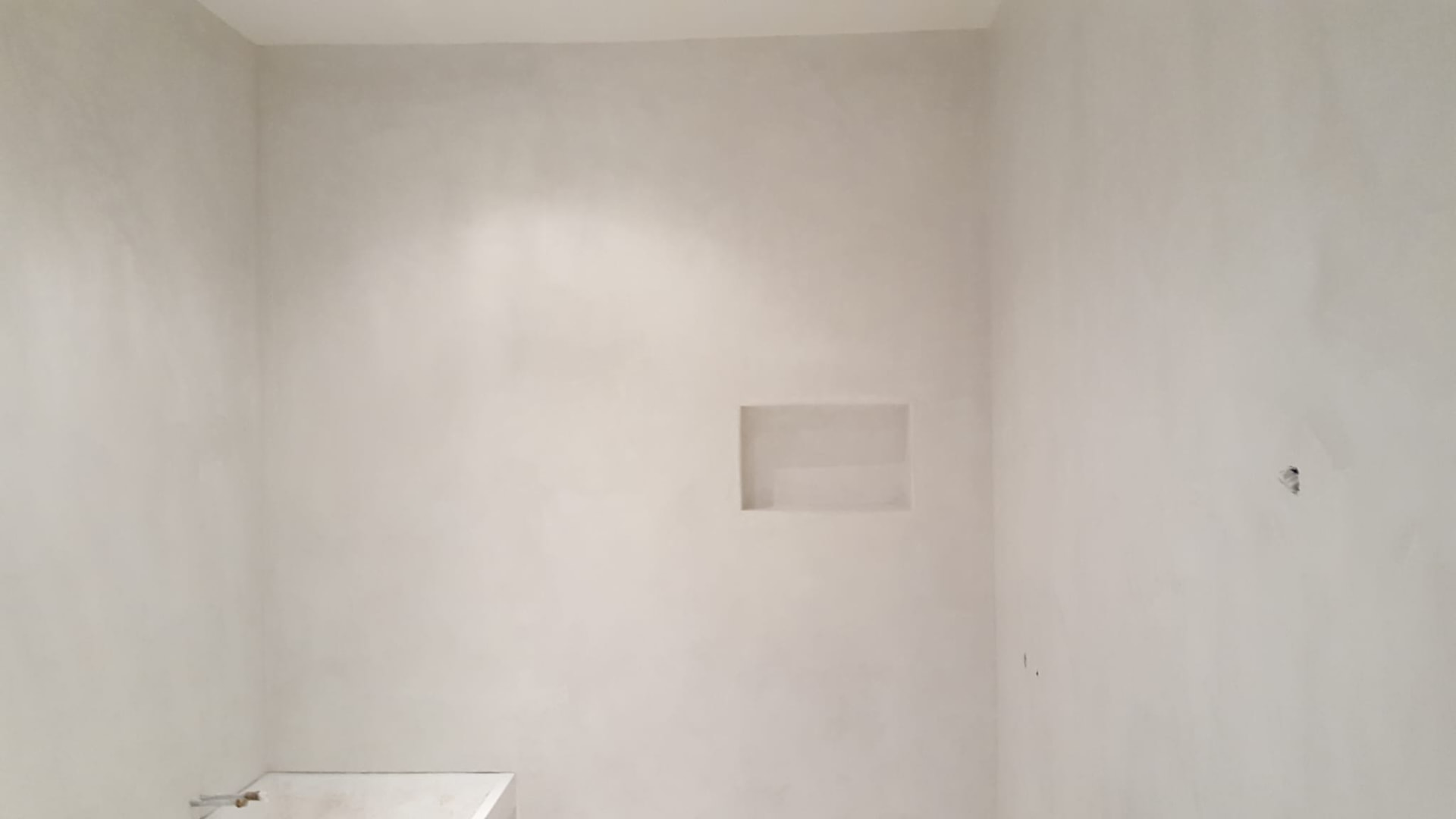 Betoncire badkamerwand met nis in een naadloze, waterdichte afwerking